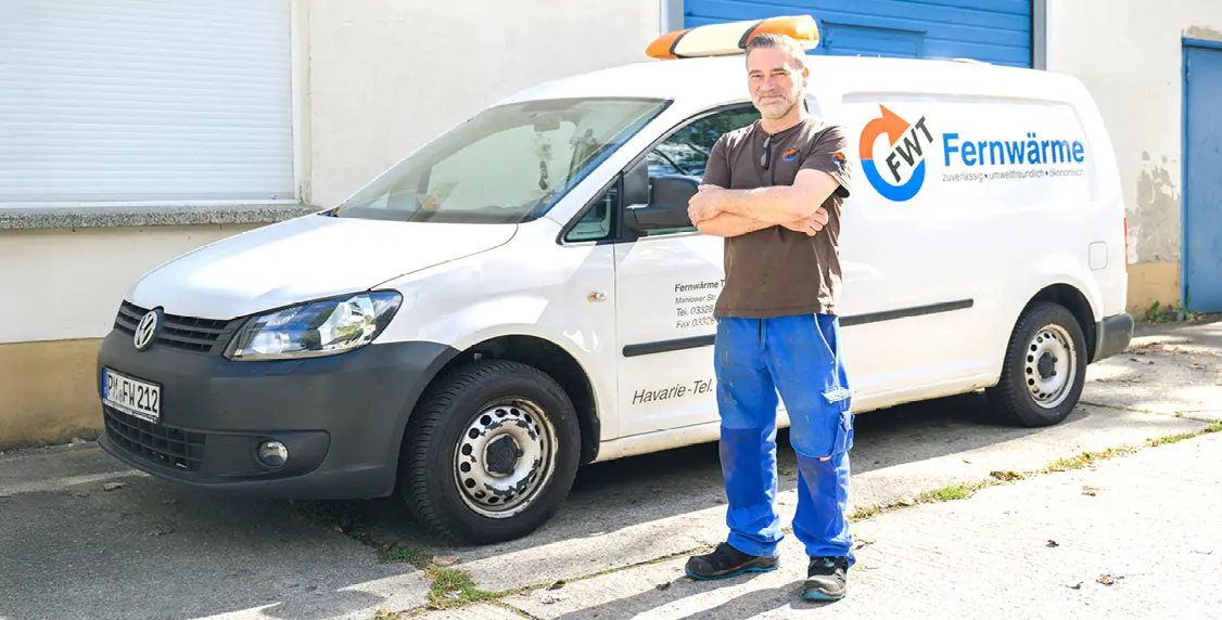 FWT - Stellenausschreibung - FWT Mitarbeiter steht vor seinem Firmenwagen